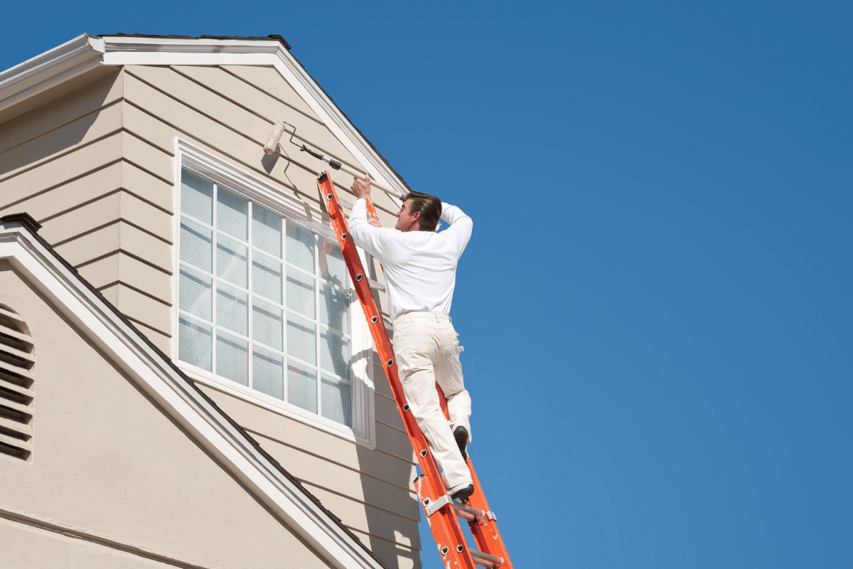 Painter on ladder painting exterior