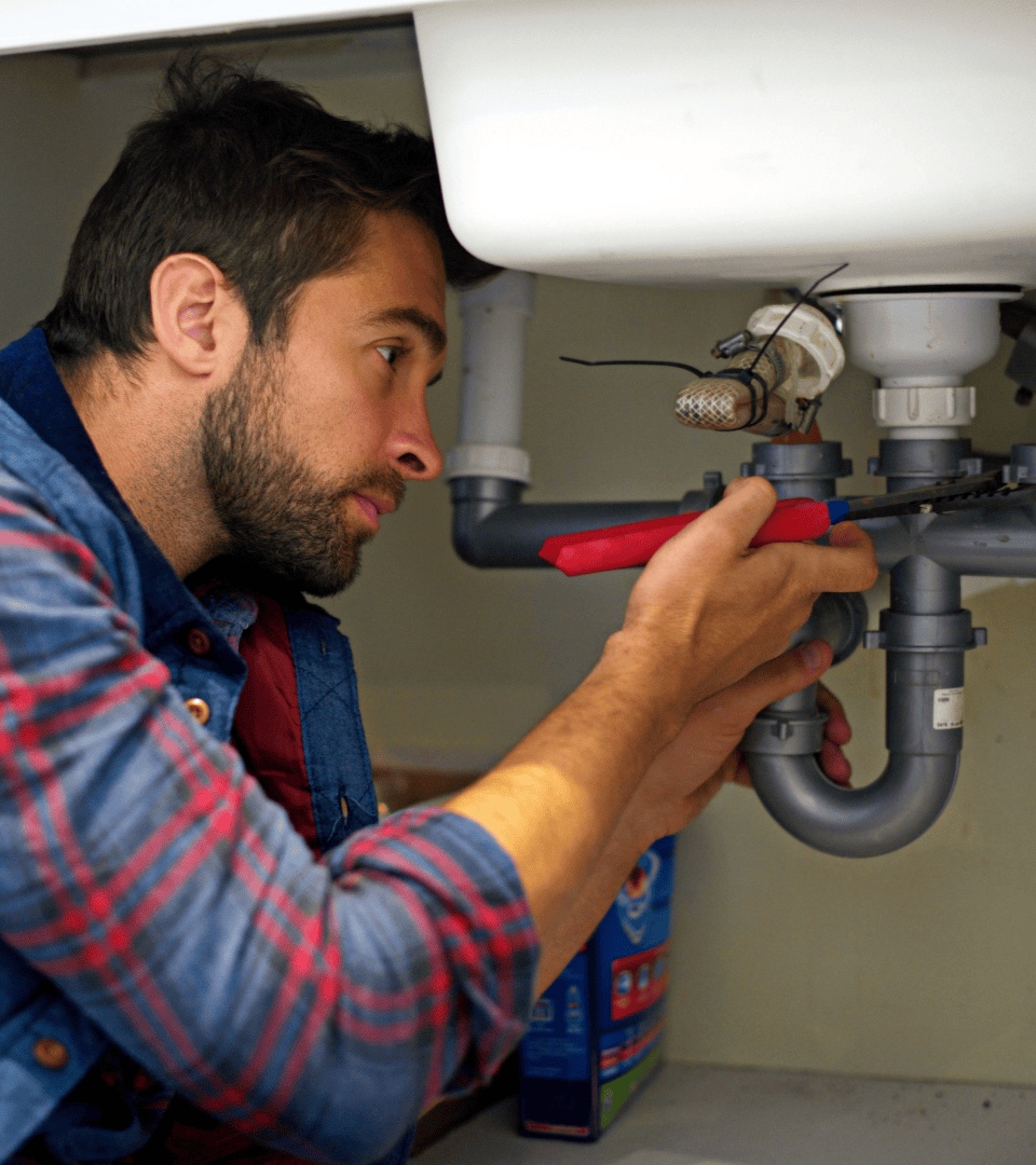 Professional plumber working under sink