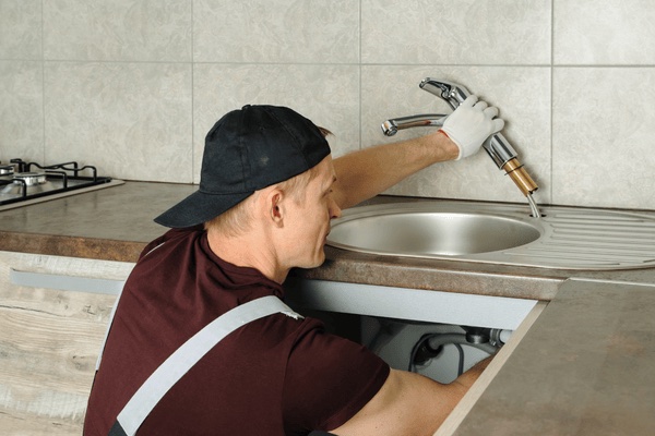 Plumber installing kitchen fixture